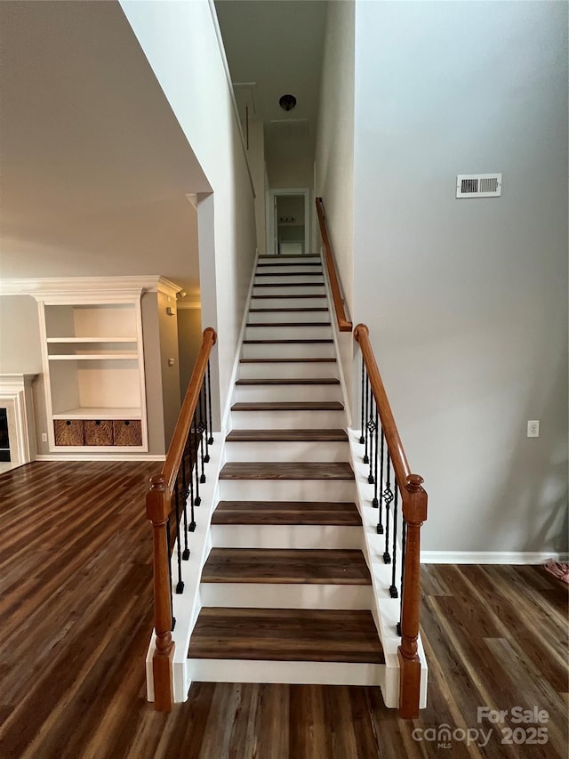 stairway with visible vents, a fireplace, and wood finished floors