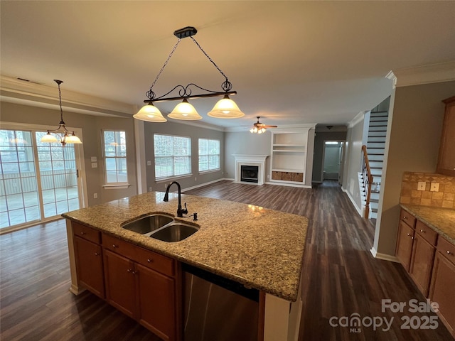 kitchen featuring hanging light fixtures, a fireplace, a sink, and light stone countertops