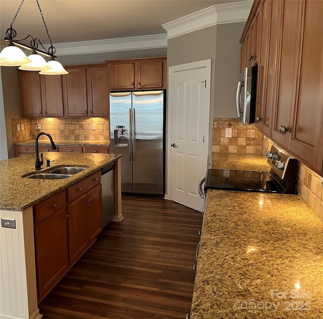 kitchen featuring light stone counters, brown cabinets, stainless steel appliances, hanging light fixtures, and a sink