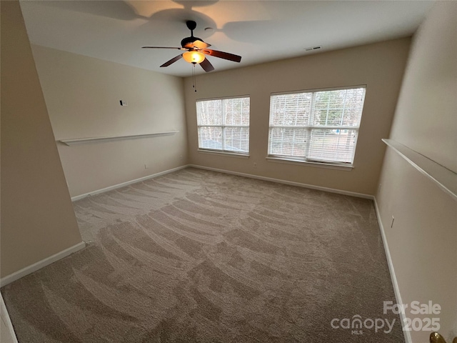 unfurnished room with a healthy amount of sunlight, ceiling fan, baseboards, and light colored carpet