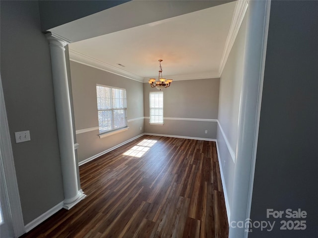 unfurnished dining area with dark wood-type flooring, an inviting chandelier, decorative columns, and crown molding