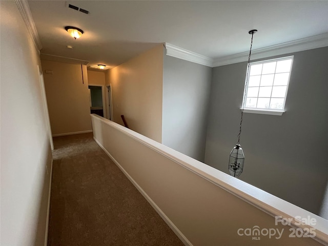 hall with carpet flooring, visible vents, baseboards, an upstairs landing, and crown molding