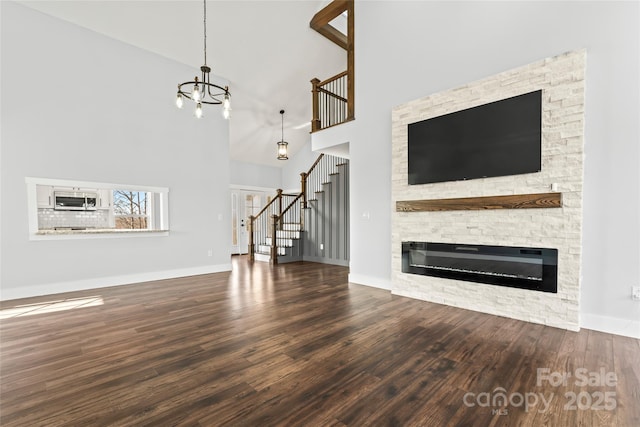 unfurnished living room featuring a chandelier, a fireplace, dark hardwood / wood-style flooring, and a high ceiling