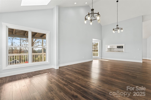 unfurnished living room featuring a skylight, dark hardwood / wood-style flooring, a chandelier, and high vaulted ceiling