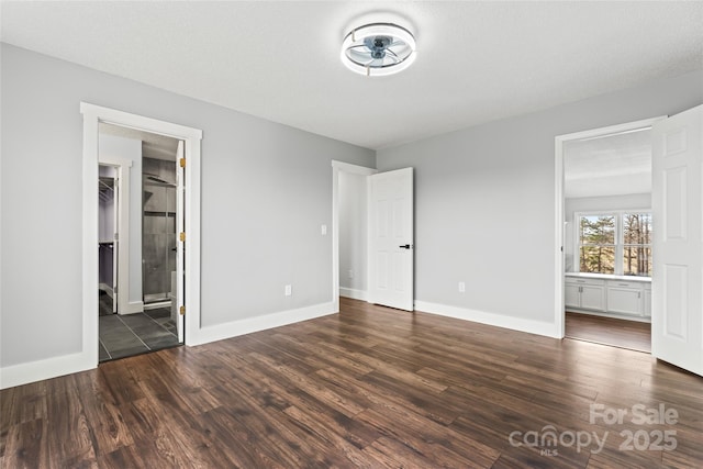 unfurnished bedroom with ensuite bath, dark hardwood / wood-style floors, and a textured ceiling