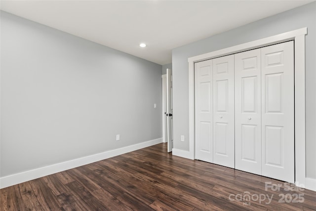 unfurnished bedroom with dark wood-type flooring and a closet