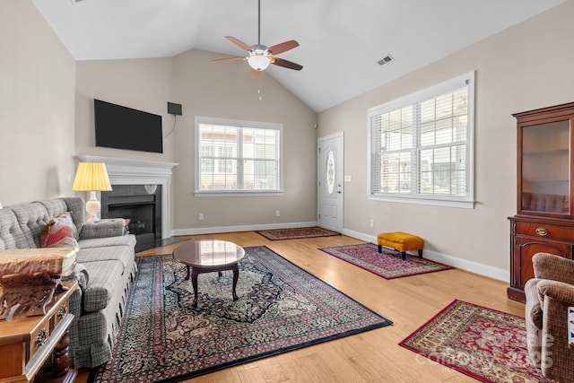 living room with lofted ceiling, hardwood / wood-style floors, a premium fireplace, and ceiling fan