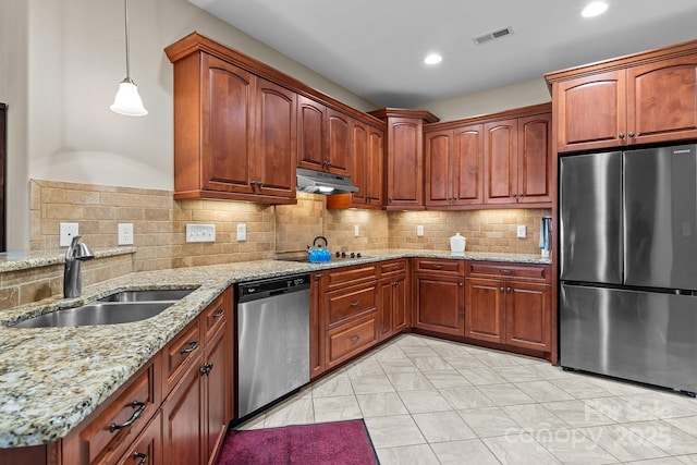 kitchen featuring sink, light stone counters, hanging light fixtures, appliances with stainless steel finishes, and decorative backsplash