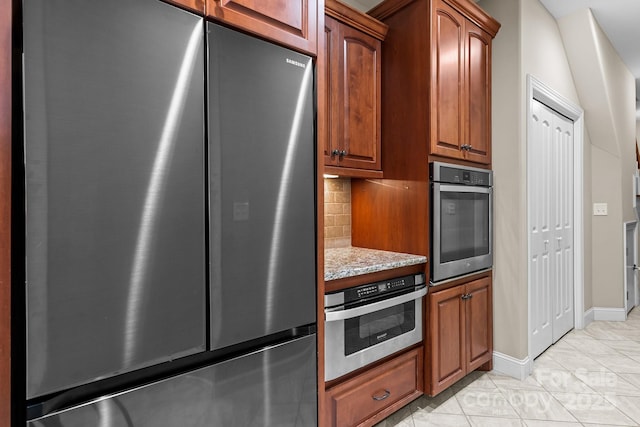 kitchen with stainless steel appliances, light stone countertops, light tile patterned floors, and decorative backsplash