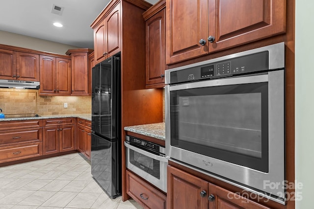 kitchen featuring tasteful backsplash, light stone countertops, light tile patterned floors, and black appliances