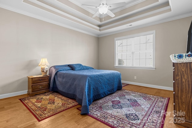 bedroom featuring crown molding, hardwood / wood-style floors, ceiling fan, and a tray ceiling