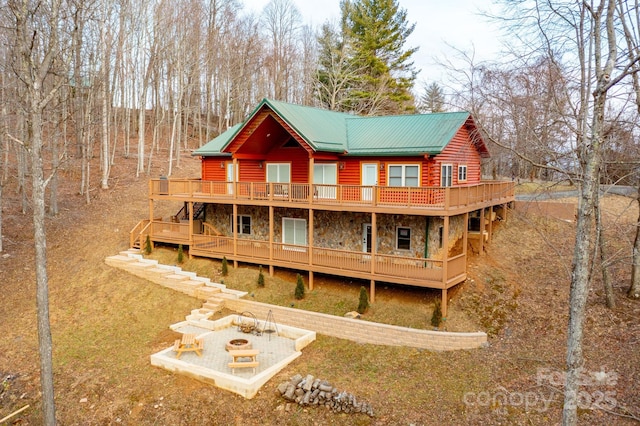 rear view of house with a wooden deck and an outdoor fire pit