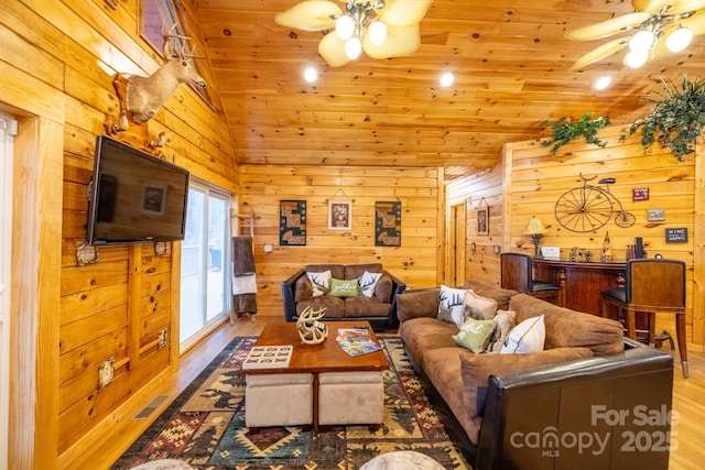 living room with lofted ceiling, wood walls, ceiling fan, and light wood-type flooring