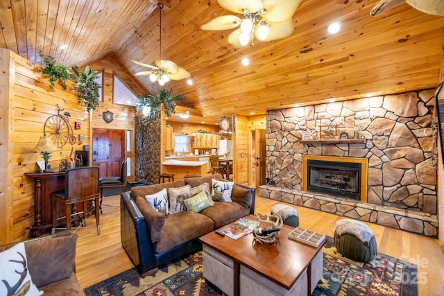 living room featuring a stone fireplace, high vaulted ceiling, wood walls, light hardwood / wood-style floors, and wooden ceiling