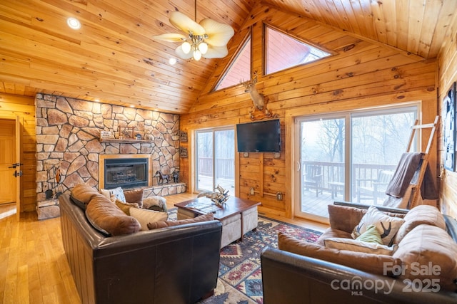 living room featuring a fireplace, a healthy amount of sunlight, wooden walls, and light wood-type flooring