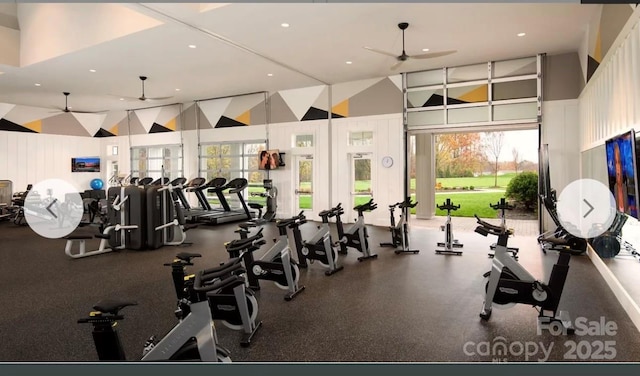 exercise room with a towering ceiling and ceiling fan