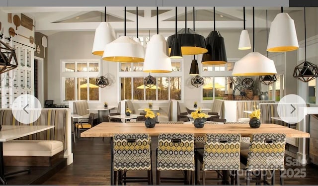 kitchen with a high ceiling, dark wood-type flooring, a kitchen breakfast bar, and decorative light fixtures