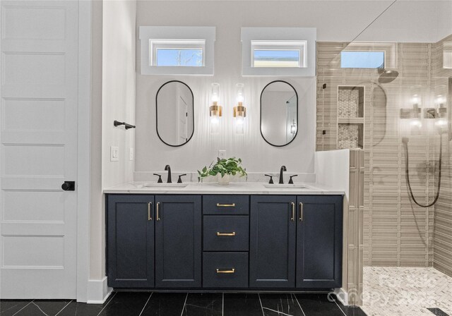 bathroom with double vanity, walk in shower, and a sink