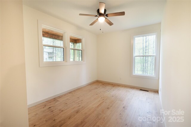 spare room featuring light wood-type flooring, a ceiling fan, baseboards, and visible vents
