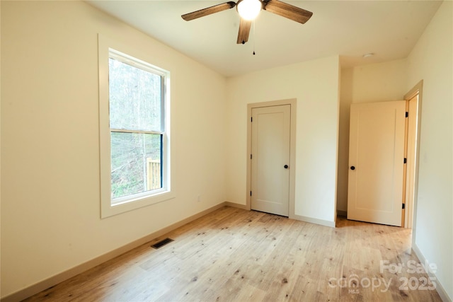 unfurnished bedroom with baseboards, visible vents, multiple windows, and light wood-style floors