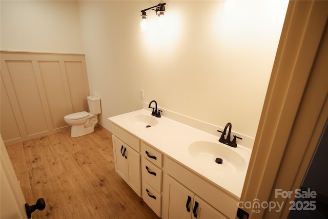bathroom featuring a sink, double vanity, toilet, and wood finished floors