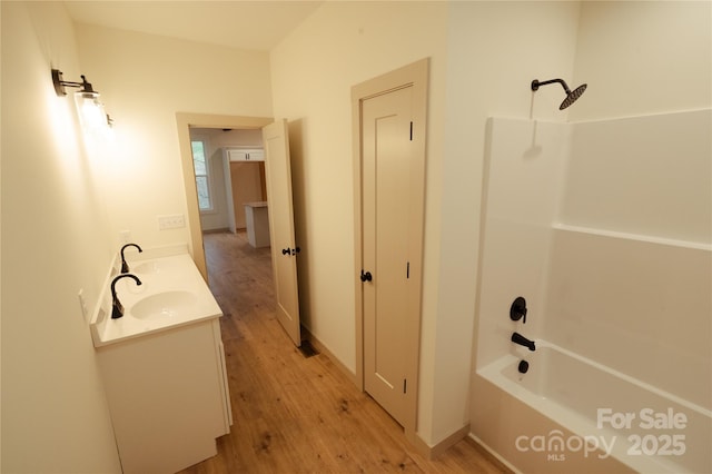 full bathroom featuring wood finished floors, double vanity, a sink, and bathtub / shower combination