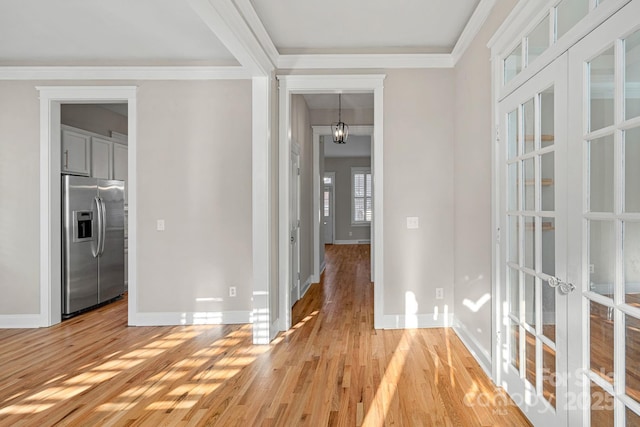 hallway featuring ornamental molding, light hardwood / wood-style floors, and french doors