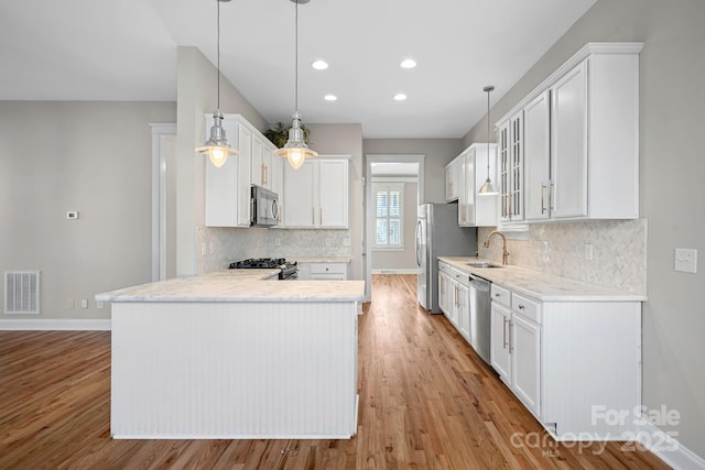 kitchen with white cabinetry, hanging light fixtures, sink, and appliances with stainless steel finishes