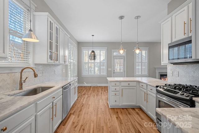 kitchen featuring white cabinetry, sink, hanging light fixtures, and appliances with stainless steel finishes