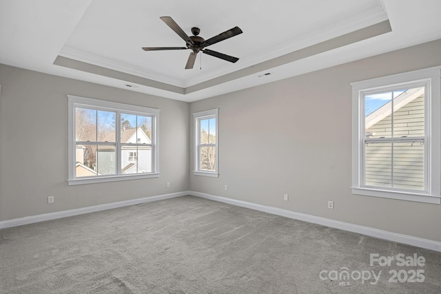 spare room featuring a tray ceiling, ornamental molding, light colored carpet, and ceiling fan