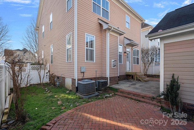 rear view of property featuring a yard, a patio area, and central air condition unit