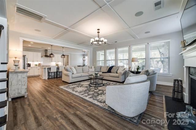 living room with coffered ceiling, a notable chandelier, and dark wood-type flooring