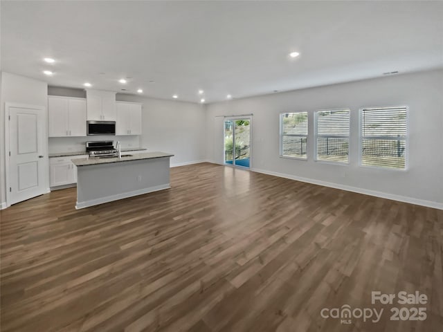 kitchen featuring dark hardwood / wood-style floors, an island with sink, sink, white cabinets, and stainless steel appliances