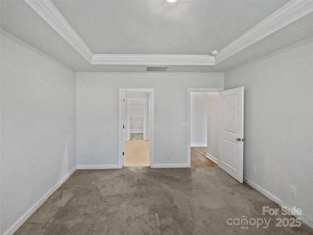 unfurnished bedroom featuring ornamental molding, light carpet, and a tray ceiling