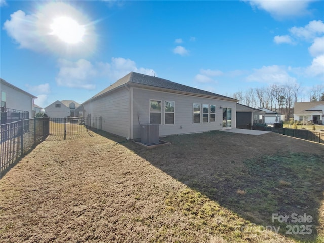 back of property featuring central AC unit, a yard, and a garage