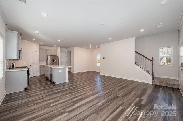 kitchen featuring sink, appliances with stainless steel finishes, dark hardwood / wood-style flooring, an island with sink, and decorative backsplash