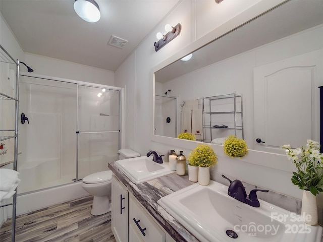 bathroom with hardwood / wood-style flooring, vanity, toilet, and a shower with shower door