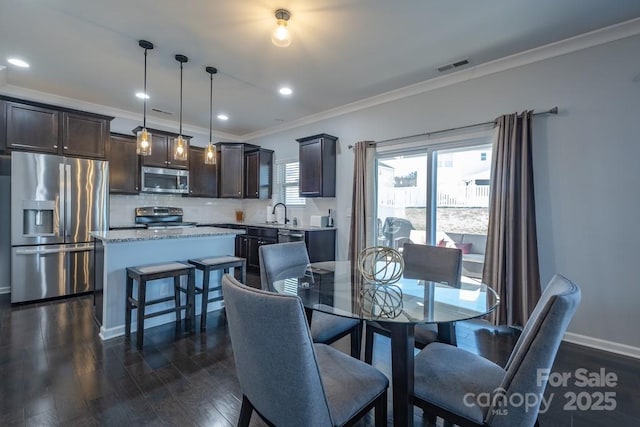 dining space with ornamental molding, dark wood-type flooring, and sink