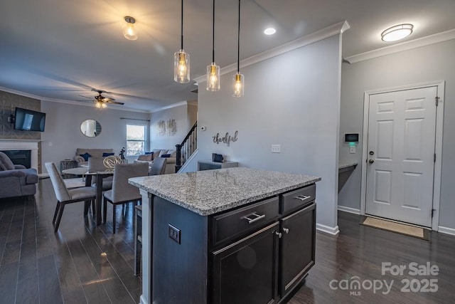 kitchen with pendant lighting, dark hardwood / wood-style flooring, ornamental molding, and a center island