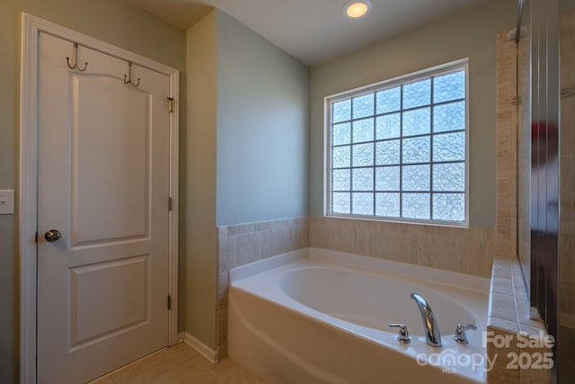 bathroom featuring tile patterned flooring, a tub to relax in, and a wealth of natural light