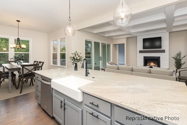 kitchen featuring sink, stainless steel dishwasher, dark hardwood / wood-style flooring, pendant lighting, and light stone countertops