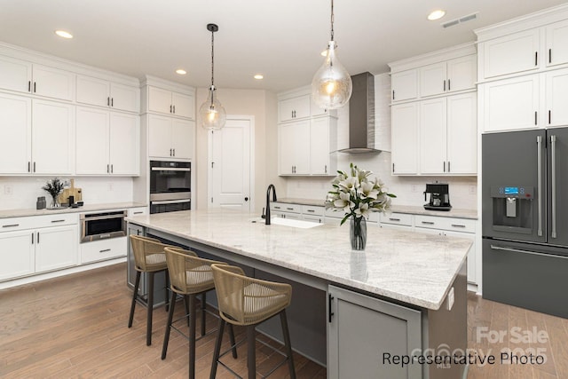 kitchen featuring a center island with sink, sink, high end refrigerator, and white cabinets