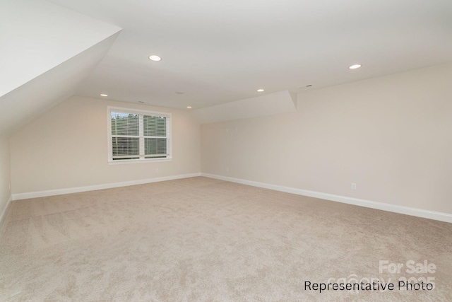 additional living space featuring light colored carpet and vaulted ceiling