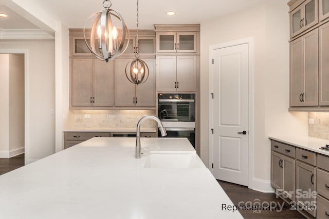 kitchen with sink, a chandelier, hanging light fixtures, black double oven, and decorative backsplash