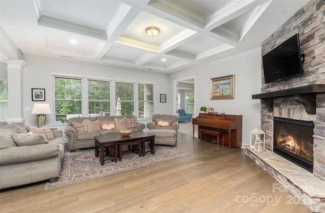 living room with beamed ceiling, a stone fireplace, coffered ceiling, and light hardwood / wood-style flooring