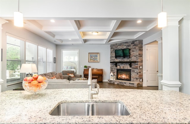 kitchen featuring pendant lighting, light stone counters, and ornate columns