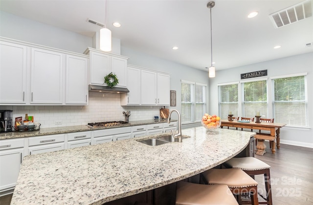 kitchen featuring stainless steel gas cooktop, decorative light fixtures, sink, and white cabinets