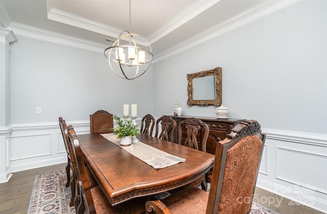 dining space featuring an inviting chandelier, dark hardwood / wood-style floors, a raised ceiling, and crown molding