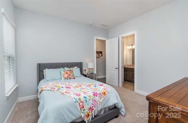 bedroom featuring light colored carpet and ensuite bath