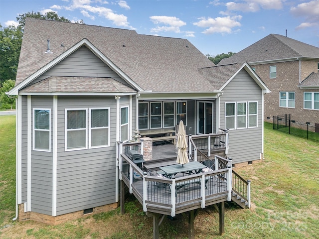 rear view of house featuring a wooden deck, a yard, and a sunroom